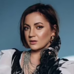 Оля Цибульська в чорній максісукні з декольте на комоді